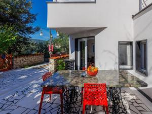 eine Terrasse mit einem Tisch und roten Stühlen in der Unterkunft Holiday Home Villa Dragica by Interhome in Labin