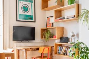 uma sala de estar com uma televisão e uma secretária com uma cadeira em Treetops - Characterful flat with parking, close to beach em Falmouth