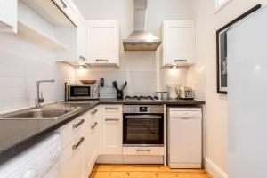 uma cozinha com armários brancos e um lavatório em Treetops - Characterful flat with parking, close to beach em Falmouth