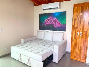 ein weißes Sofa in einem Zimmer mit einem Gemälde an der Wand in der Unterkunft El Castillo - Adults only in Ojochal