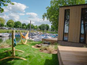 un patio con un parque infantil con barcos en un puerto deportivo en Holiday Home Tiny River House-1 by Interhome, en Maurik