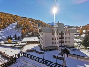 un edificio con una montaña cubierta de nieve en el fondo en Hostdomus - Oslo Apartments en Borgata Sestriere