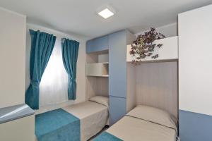 una piccola camera con due letti e una finestra di Village Camping Joker a Cavallino-Treporti