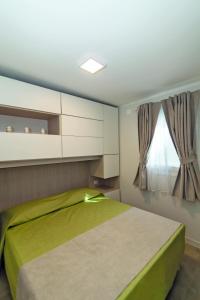 a bedroom with a green bed and a window at Village Camping Joker in Cavallino-Treporti