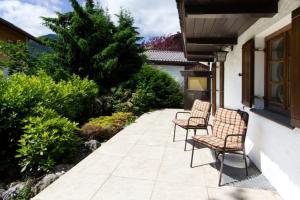 a patio with three chairs and a tree at Hölzlhaus - a74066 in Mittenwald