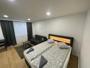 een slaapkamer met een bed, een stoel en een bank bij Akmene Center Apartment in Naujoji Akmenė