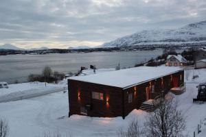 a house in the snow next to a body of water at Tromsø stunning Luxury apart A in Larseng