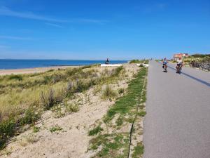 un grupo de personas montando bicicletas por una carretera junto a la playa en Le Normandy 5star en Cadzand