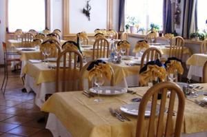 un gruppo di tavoli in un ristorante con tovaglia gialla di Hotel Zanon a Ziano di Fiemme