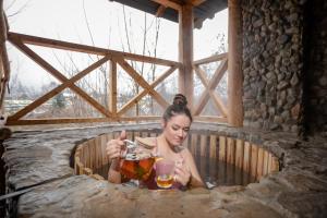uma mulher sentada numa banheira segurando uma bebida em Gutsulska rodzynka em Yaremche