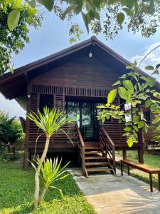 Casa de madera con escalera y banco en เพชรพิชชารีสอร์ท, en Ban Bang Kham