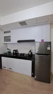 a kitchen with a stainless steel refrigerator and white cabinets at Lincoln Tower Podomoro Apartment in Medan