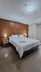 een grote slaapkamer met een groot bed met houten wanden bij Lincoln Tower Podomoro Apartment in Medan