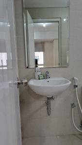 Un baño con un lavabo blanco y un espejo. en Lincoln Tower Podomoro Apartment, en Medan
