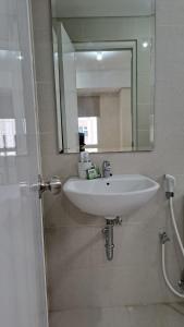 een badkamer met een witte wastafel en een spiegel bij Lincoln Tower Podomoro Apartment in Medan