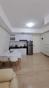 een keuken en een woonkamer met een tafel en stoelen bij Lincoln Tower Podomoro Apartment in Medan