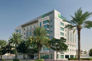a tall white building with palm trees in front of it at Holiday Inn Express Dubai, Jumeirah, an IHG Hotel in Dubai