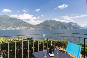 a table with wine bottles and glasses on a balcony overlooking the water at Studio Apartment Lake Views in Acquaseria +7 photos