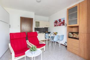 a living room with red chairs and a table at Studio Apartment Lake Views in Acquaseria