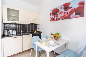 a kitchen with a white table and blue chairs at Studio Apartment Lake Views in Acquaseria