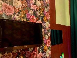 een flatscreen-tv aan een muur met bloemen bij Dinkel Verblijf in Denekamp