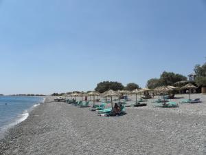 a beach with many chairs and umbrellas and the ocean at Megim Hotel in Palaiochora