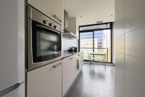 a white kitchen with a large tv on the wall at chicStays Apartment Ciutadella Park in Barcelona