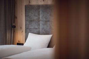 sypialnia z łóżkiem z białą poduszką w obiekcie ROUDA luxury retreat am Kronplatz w mieście Valdaora