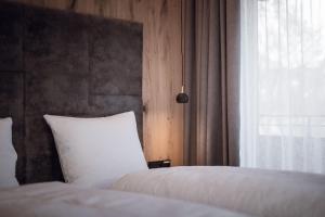 1 dormitorio con 2 camas blancas y ventana en ROUDA luxury retreat am Kronplatz, en Valdaora