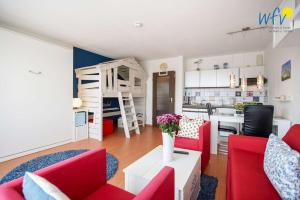 a living room with red furniture and a kitchen at Holiday Residenz - Ferienwohnung "Kuestenkind" in Borkum