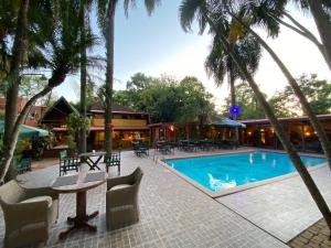 a resort with a swimming pool and palm trees at Boutique Hotel De La Fonte & Restaurant in Puerto Iguazú