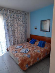 a bedroom with a large bed with blue pillows at Onisillos Hotel in Larnaka