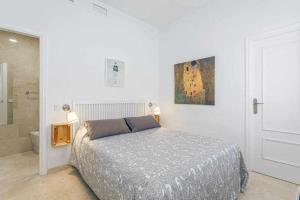 ein weißes Schlafzimmer mit einem Bett und einem Badezimmer in der Unterkunft Santa Cruz Parking incluido in Sevilla