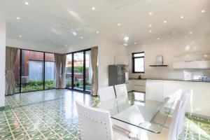 果亞舊城的住宿－Luxury 3BHK Villa with Private Pool near Anjuna，厨房以及带玻璃桌和白色椅子的用餐室。