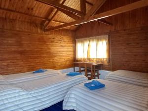 a bedroom with two beds and a table and a window at ESTANCIA LA SERENA in Perito Moreno