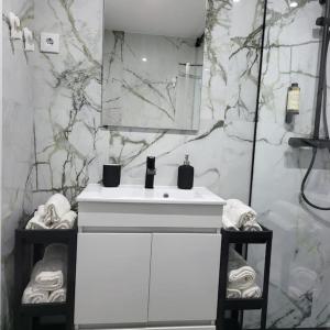 a bathroom with a white sink and marble walls at Nandos Apartement in Costa da Caparica