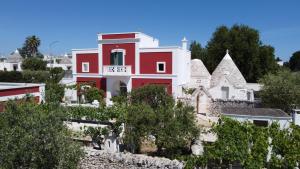 una casa roja y blanca en una colina con árboles en Masseria Trulli sull'Aia, en Cisternino