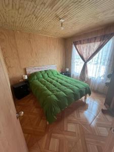 - un grand lit vert dans une chambre dotée d'un plafond en bois dans l'établissement Cabañas akrilu, à Puchuncaví