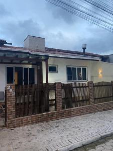 a home with a brick fence and a house at Casa Temporada in Camboriú