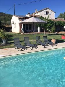 a group of chairs and an umbrella next to a swimming pool at La Vignarelle in Callas