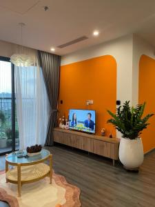 ein Wohnzimmer mit orangefarbenen Wänden und einem Flachbild-TV in der Unterkunft R102 Vinhomes Ocean Park homestay in Hanoi