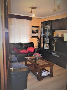a living room with a black leather couch and a coffee table at Habitaciones en Aviles in Avilés