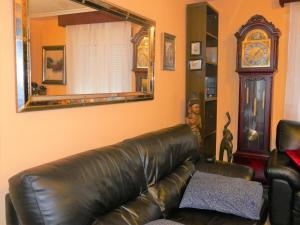 un sofá de cuero en una sala de estar con espejo en Habitaciones en Aviles en Avilés