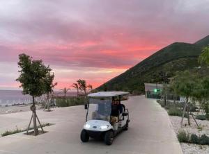 een golfkar op een stoep naast het strand bij AURA by DAMM's Villas in Llogara