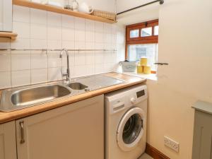 a kitchen with a sink and a washing machine at Dere Cottage in Richmond