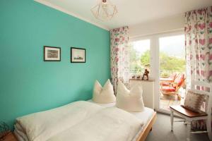 um quarto com paredes azuis e uma cama com almofadas brancas em Chalet Manhard em Pfronten