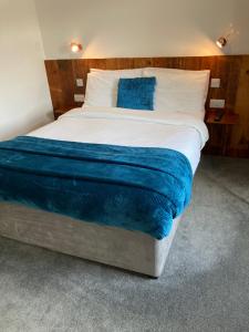 um quarto com uma cama grande e lençóis azuis em Jersey Villa Guest House em Warwick