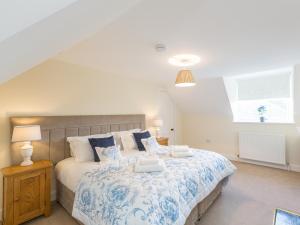 a bedroom with a large bed with blue and white sheets at Chauffeur's Cottage with Hot Tub in Cray