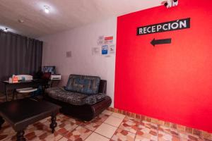 a waiting room with a red wall with a chair and a red door at Hotel Bello Caribe Express in Cozumel