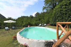 a swimming pool in a garden with chairs and an umbrella at La Casetta in Coreglia Antelminelli